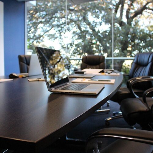 Inventario del parque informático Portátiles de empresa abiertos sobre la mesa de una sala de reuniones